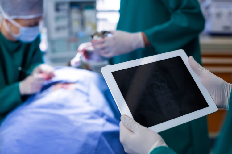 Equipe médica em centro cirúrgico utilizando tecnologia com monitoramento térmico durante procedimento de cirurgia plástica.
